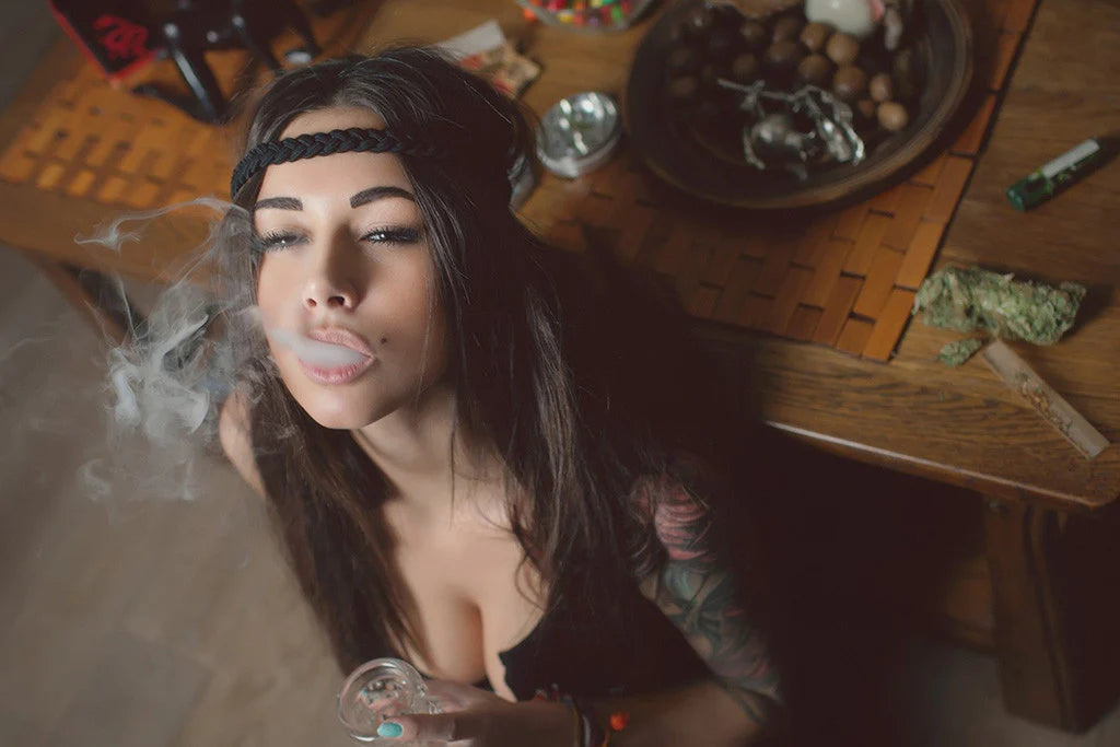 Woman smoking cannabis with a rolling table and various items in the background